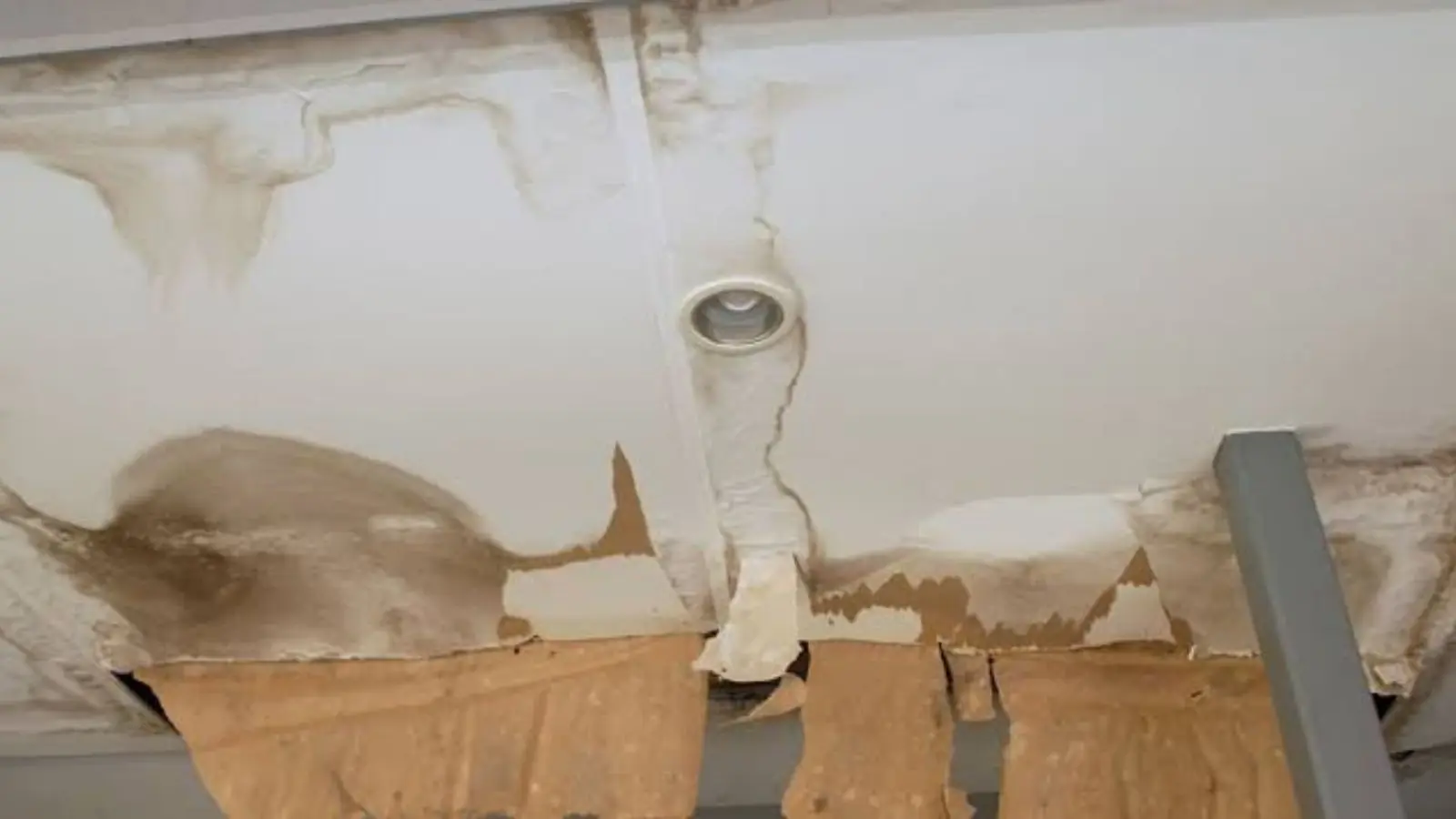 Water-stained ceiling with a leak coming from around a light fixture