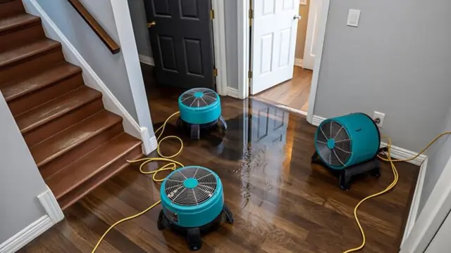 Air movers drying a wet wood floor near a staircase